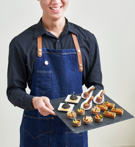 An image of a butler holding a tray of canapes